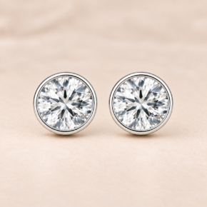 Front-facing pair of sterling silver round clear CZ stud earrings with smooth rub-over bezel settings.