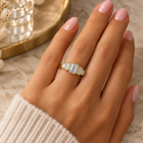 Yellow gold five-stone emerald-cut lab-grown diamond ring worn on the ring finger