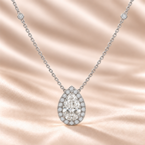9ct white gold pear lab-grown diamond halo necklace with diamond-set chain stations on a warm champagne background
