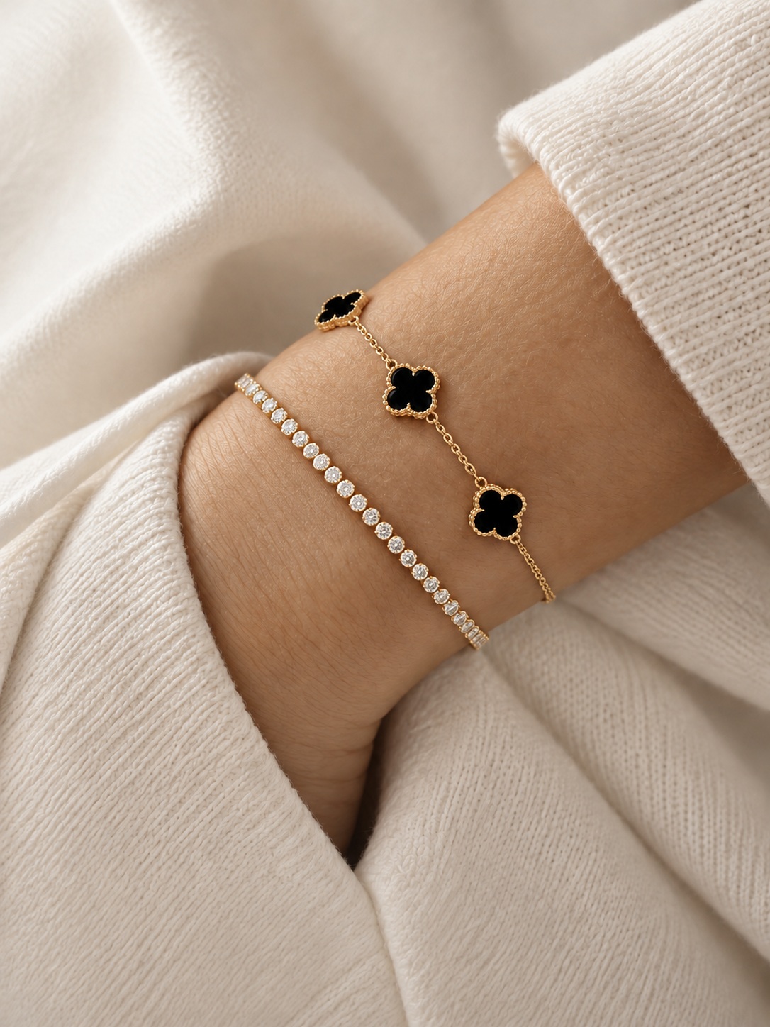 Black clover and diamond bracelets worn on a wrist