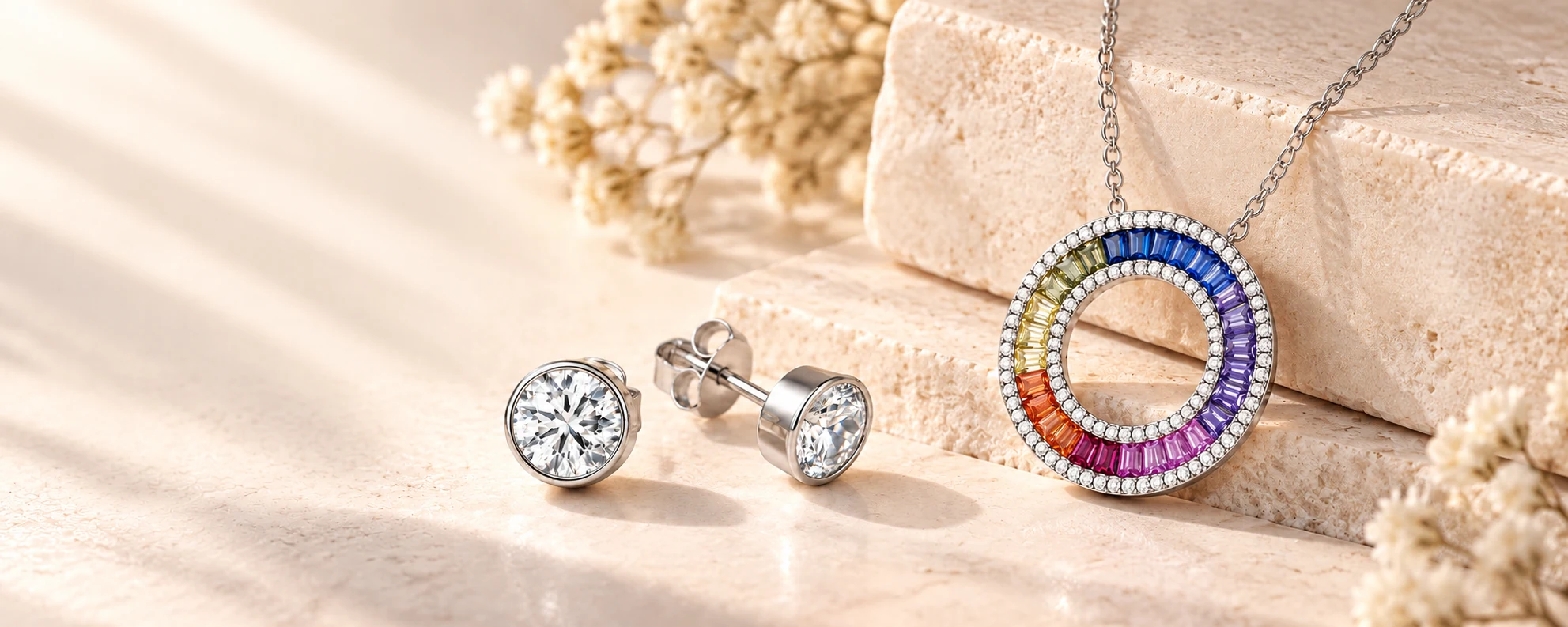 Silver-tone CZ rub-over studs and a multicoloured CZ Circle of Life necklace on warm ivory stone