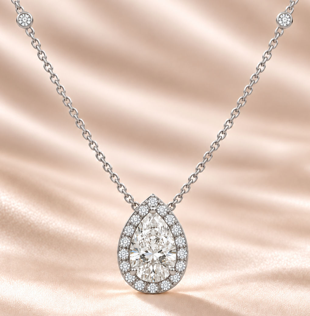 Pear-shaped lab-grown diamond halo necklace with both diamond-set chain stations on champagne fabric